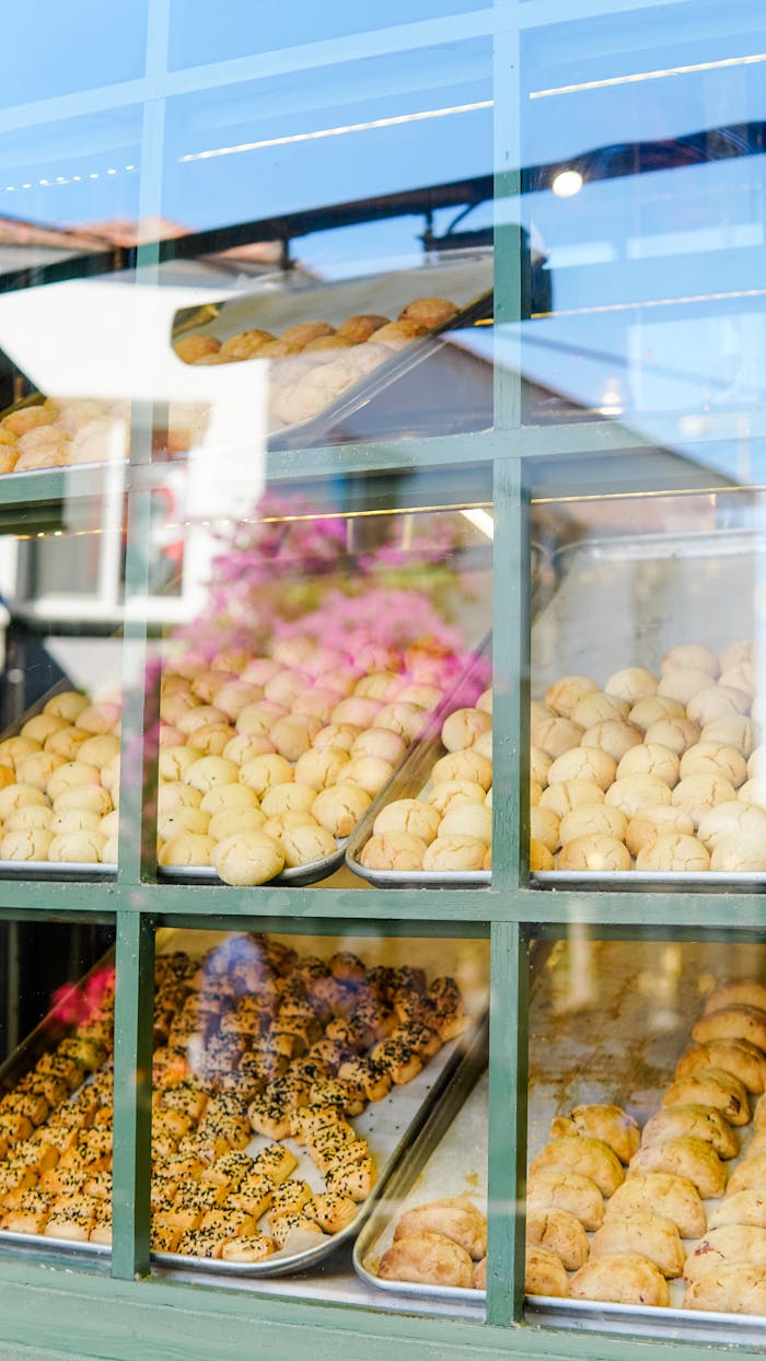 Freshly baked goods displayed in a bakery window in Alaçatı, İzmir, showcasing a variety of pastries and buns.